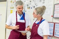 Zwei Personen in Küchenkleidung besprechen einen Plan