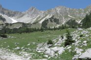 Hohe Kalkberge umrahmen eine Bergmattenlandschaft.