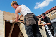 Zwei Männer bei der Arbeit an einem Holzgebäude