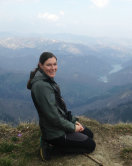 Junge Frau mit langen dunklen Haaren sitzt auf einem Berg in den Alpen.