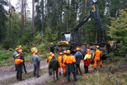 Menschen in Warnkleidung stehen um einen Harvester herum.