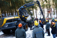 Menschen mit Schutzhelmen stehen um einen Harvester herum