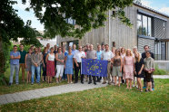 Ein Gruppenbild von Menschen, die sich um eine blaue Flagge herum positioniert haben