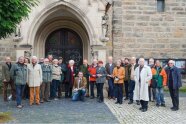 Eine Gruppe Menschen steht im Halbkreis vor einer Kirchenportal