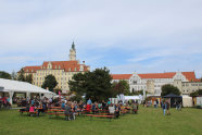 Im Hintergrund ein Schloss, davor Biertische und Stände