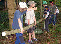 Fünf Kinder tragen einen Baumstamm