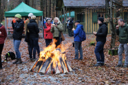 Personen stehen vor einem Lagerfeuer im Wald