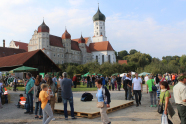 Menschen spazieren in einem Park vor einer Klosterkirche