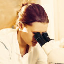 Frau schaut in ein Mikroskop