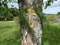 Gesicht aus Gras und Blüten an einem Baum