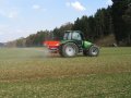 Ein Traktor mit Mineraldüngerstreuer fährt über ein Feld.
