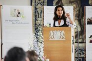 Eine Frau steht an einem Rednerpult und hält eine Rede