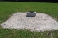 Auf einer Weide ist eine runde Wassertränke aus Beton, darum ein bestigter Umplatz