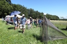 Ein Netz ist auf einer Wiese aufgebaut ähnlich wie ein Zelt, im Hintergrund stehen mehrere Personen