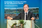 Prof. Dr. Kurt-Jürgen Hülsbergen, TU München, Lehrstuhl für Ökologischen Landbau beim Einführungsvortrag steht hinter einem Pult, Im Hintergrund ein Rollup der TUM.