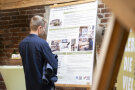 Informationstafel mit Bildern und Text über das Kleeberger Kistl, vor der ein Mann darauf blickend steht.
