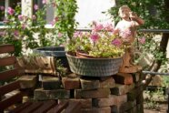 Geranien, eine Figur und verschiedene Blumen dekorieren den Garten