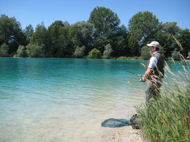 Angler steht an einem Baggersee