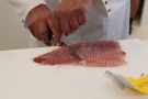 Person schneidet ein Fischfilet ein
