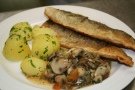 zwei Stück Fisch paniert auf einem Teller mit Kartoffeln