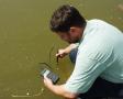Mann hält ein Messgerät in einem Teich