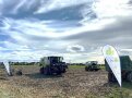 Verschiedene Erntemaschinen auf Feld mit LfL Fahne im Vordergrund