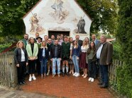 Eine Gruppe Menschen steht vor einer kleinen Kapelle