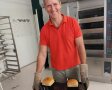 Bäcker zeigt Backblech mit gebackenen Broten