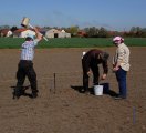 Drei Personen nehmen Bodenproben auf einem Feld