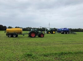 zwei Traktoren mit Düngetechniken Breitverteilung und Schleppschuh auf Feld