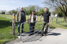 Dr. Christian Mendel und Giulia Kriegel von der LfL mit Martin Bartl vom Verband Bayerischer Schafhalter stehen vor einem Weideschutztor. 
