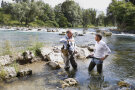 LfL-Präsident Stephan Sedlmayer und Willi Ruff, Vizepräsident des Landesfischereiverbandes stehen in Anglerhosen mitten im Wasser und diskutieren.