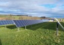 Photovoltaik-Anlage auf grüner Wiese vor blauem Himmel