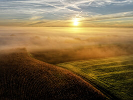 Drohnenfoto mit Feldern vor untergehender Sonne.