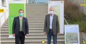 Zwei Männer stehen mit Mund-Nasen-Schutz vor einem Gebäude