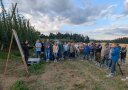 Mitarbeiterin erläutert den Zuhörern an einer Schautafel im Feld.