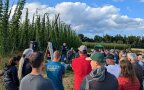 Ein LfL-Mitarbeiter begrüßt die Teilnehmer vor einem Hopfengarten.