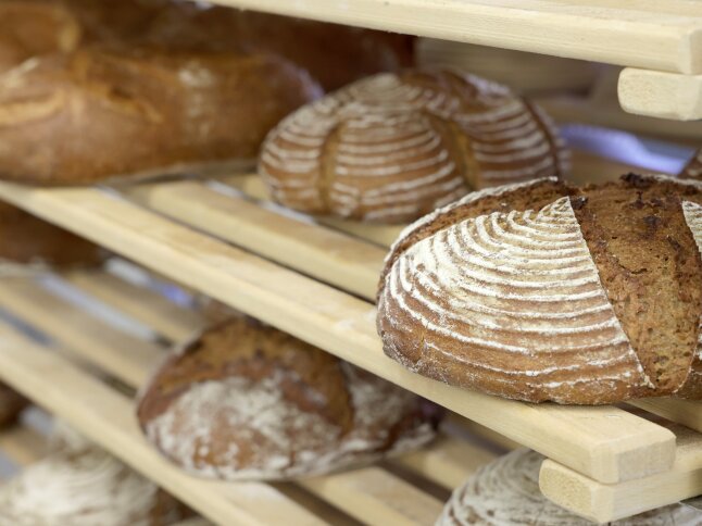 Brotlaibe in einem Holzregal.